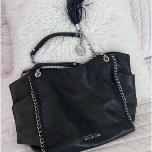 Michael Kors  black purse with metal chain accent with two side pockets.
